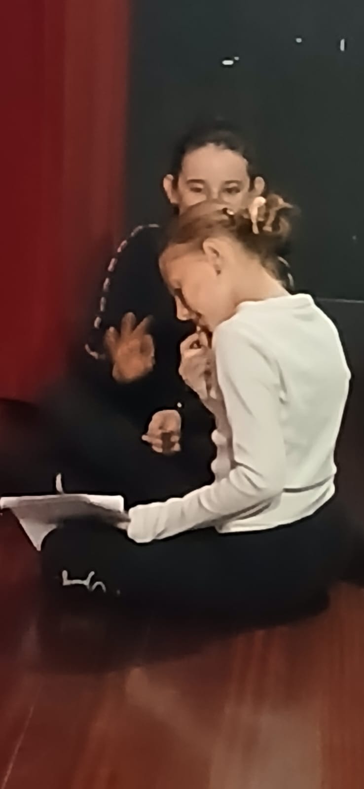 Deux jeunes filles assises au sol, travaillant un texte ensemble