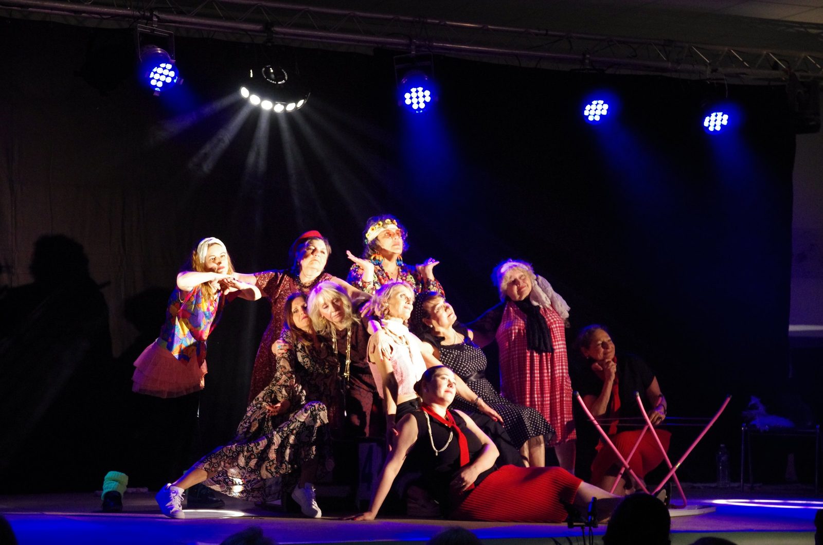 Troupe en costumes sur scène, éclairée par des projecteurs bleus en pleine représentation